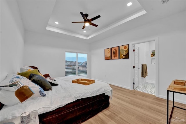 bedroom featuring baseboards, a raised ceiling, wood finished floors, and recessed lighting