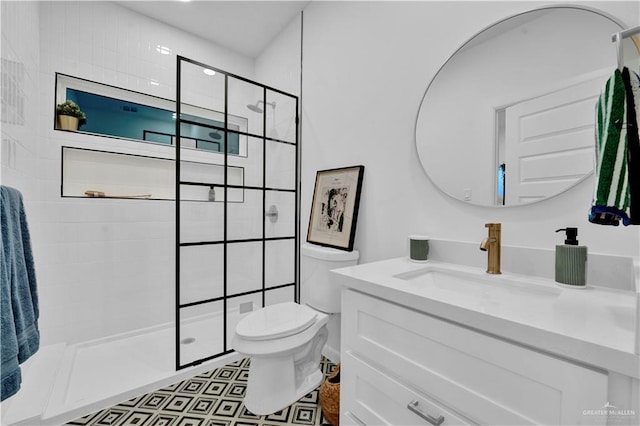 full bath with vanity, a tile shower, and toilet