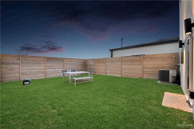 yard at dusk featuring cooling unit and a fenced backyard