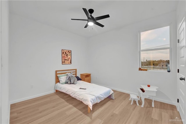 bedroom with light wood finished floors, baseboards, and a ceiling fan