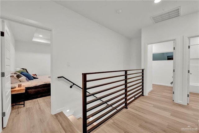 hall with recessed lighting, visible vents, light wood finished floors, and an upstairs landing