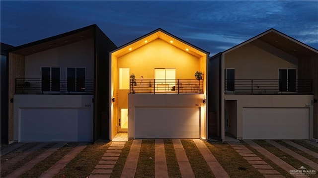 modern home with a garage, driveway, a balcony, and stucco siding