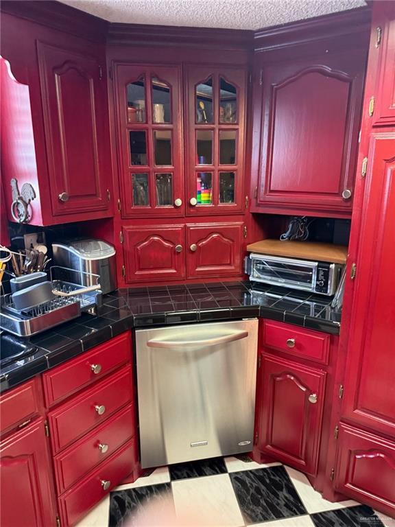 1712 N 1st St, Mcallen, TX 78501 - kitchen featuring a toaster, a textured ceiling, dark countertops, glass insert cabinets, and dishwasher