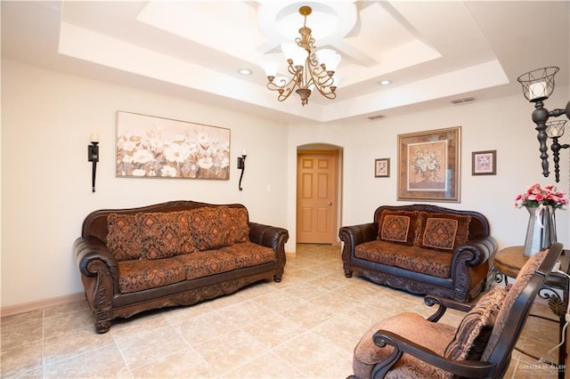 living room with arched walkways, a tray ceiling, a chandelier, and baseboards