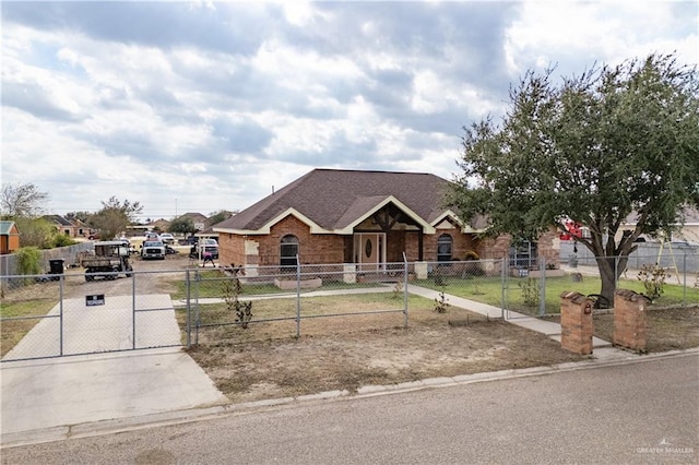 view of front of house with a fenced front yard, a gate, brick siding, and roof with shingles