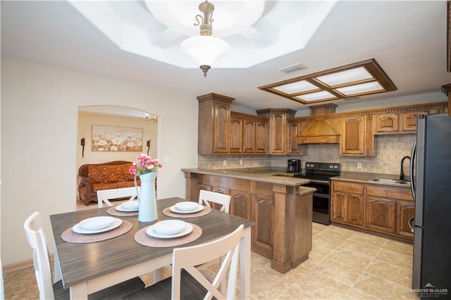 kitchen featuring a peninsula, a sink, visible vents, appliances with stainless steel finishes, and custom exhaust hood