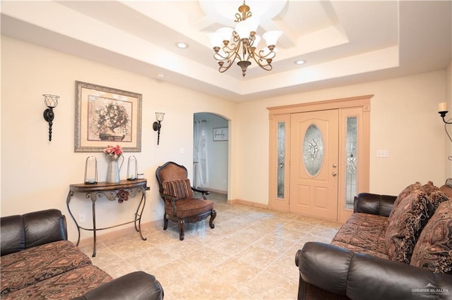 living area with arched walkways, baseboards, a raised ceiling, and a notable chandelier