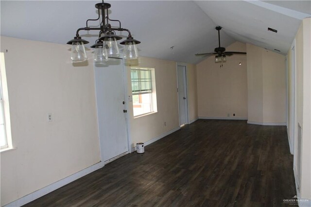 interior space featuring ceiling fan with notable chandelier, dark hardwood / wood-style flooring, and vaulted ceiling