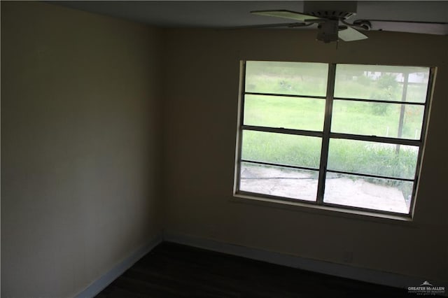 spare room with ceiling fan, plenty of natural light, and dark wood-type flooring