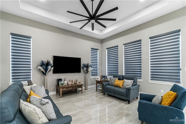 living room featuring a raised ceiling and ceiling fan