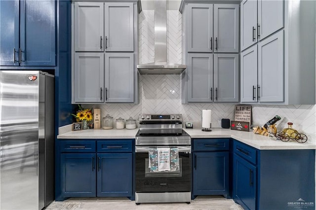 kitchen featuring wall chimney exhaust hood, appliances with stainless steel finishes, blue cabinetry, and backsplash