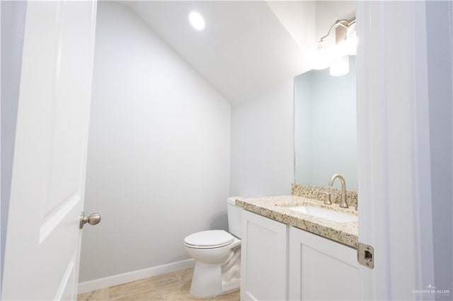 bathroom with tile patterned flooring, vanity, toilet, and vaulted ceiling