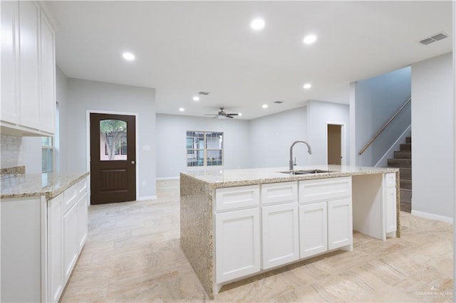 kitchen featuring ceiling fan, a center island with sink, white cabinets, and sink