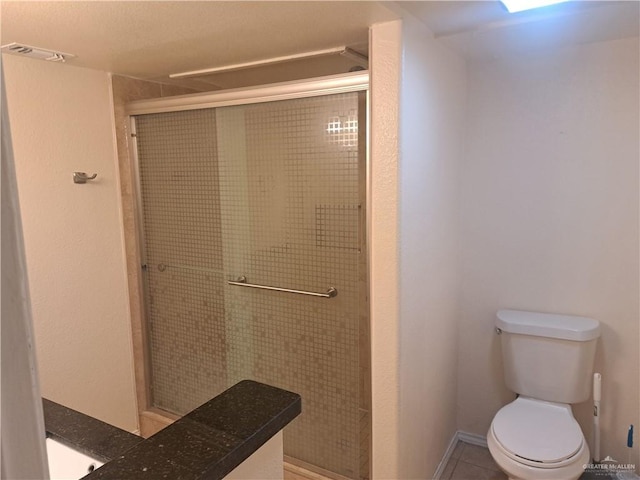 bathroom featuring toilet, tile patterned floors, and a shower stall