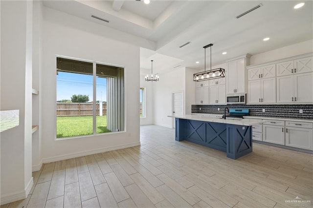 2413 N Gaytan Ave, Edinburg, TX 78542 - kitchen with stainless steel microwave, electric range oven, a chandelier, light wood-type flooring, and decorative backsplash