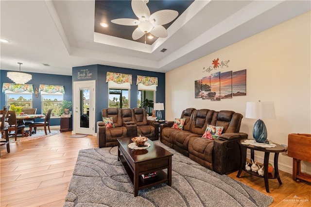 living room featuring a raised ceiling, ceiling fan, and wood-type flooring