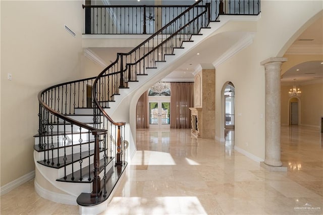 stairs featuring crown molding, french doors, a towering ceiling, and an inviting chandelier