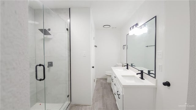 full bath featuring double vanity, a shower stall, wood tiled floor, and a sink