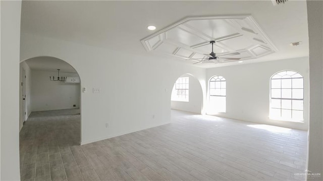 spare room featuring arched walkways, visible vents, light wood-style flooring, ceiling fan, and coffered ceiling