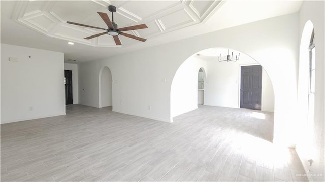 empty room featuring a ceiling fan, arched walkways, coffered ceiling, and light wood finished floors