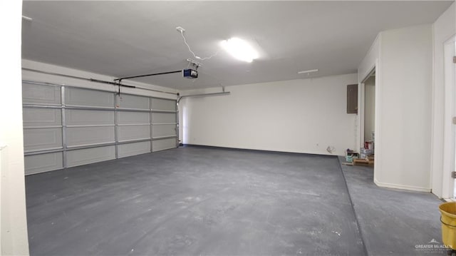 garage with a garage door opener, electric panel, and baseboards