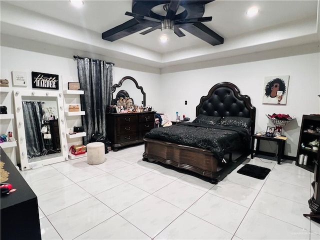 bedroom with light tile patterned floors, a tray ceiling, and ceiling fan