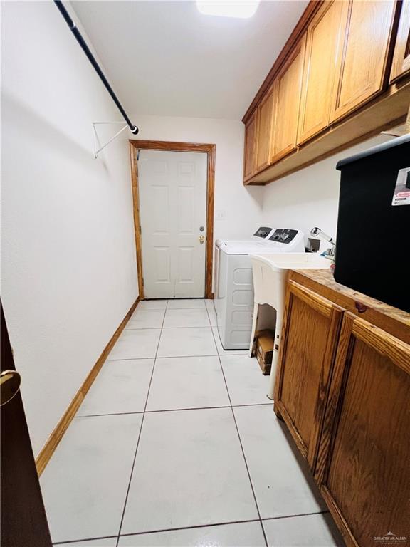 washroom with cabinets, washer and dryer, and light tile patterned floors