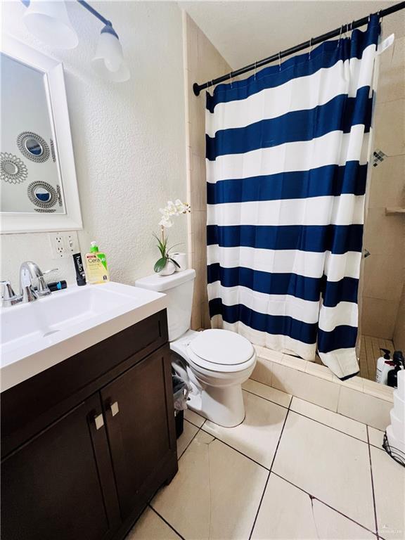 bathroom featuring vanity, tile patterned floors, toilet, and walk in shower