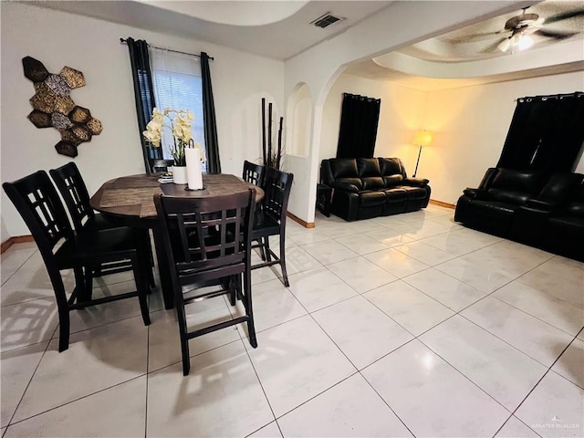 tiled dining space featuring ceiling fan and a tray ceiling