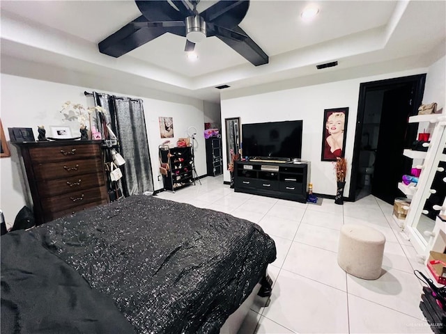 bedroom with light tile patterned flooring, ceiling fan, and a raised ceiling