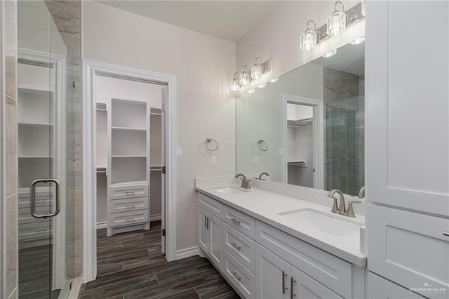 full bath with a stall shower, a walk in closet, a sink, and double vanity