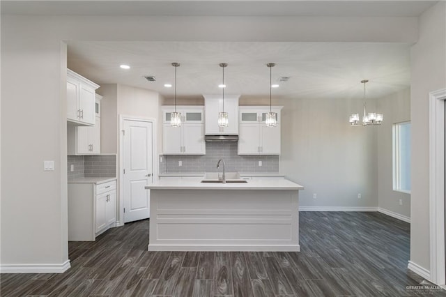 kitchen with dark wood-type flooring, a sink, white cabinets, light countertops, and glass insert cabinets