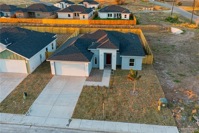 view of front of house with an attached garage, a shingled roof, driveway, a residential view, and stucco siding