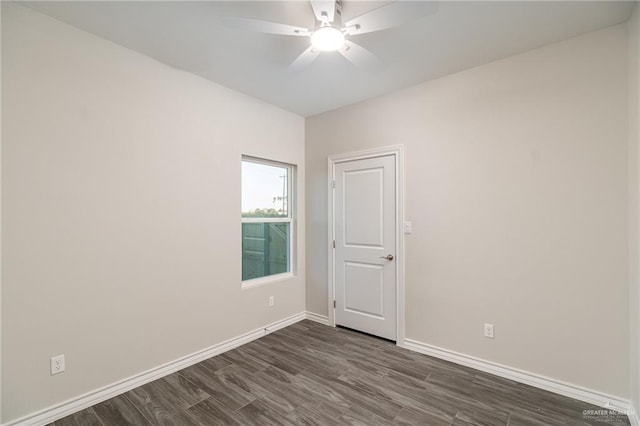 empty room featuring dark wood-type flooring, a ceiling fan, and baseboards