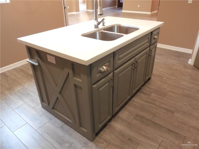 5421 San Diego Dr, Edinburg, TX 78542 - kitchen featuring a sink, an island with sink, baseboards, light countertops, and light wood-style flooring