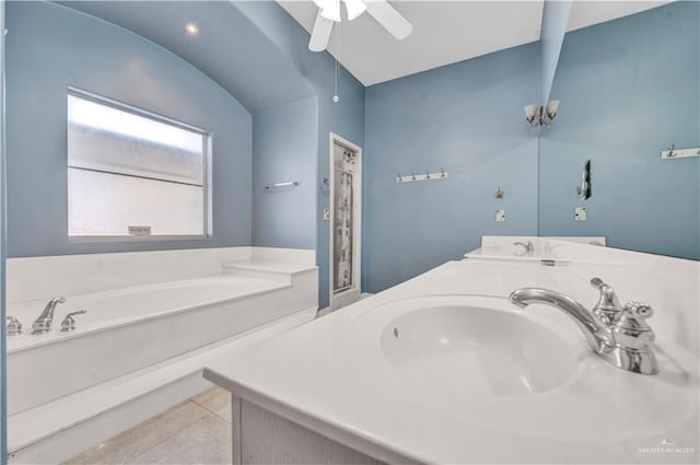 bathroom featuring vanity, a bath, vaulted ceiling, and tile patterned floors