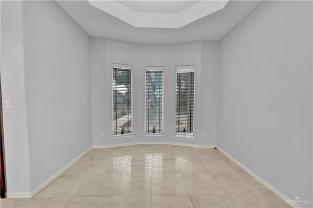 tiled empty room with a tray ceiling