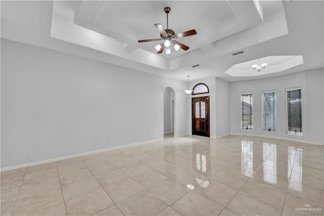 spare room with a tray ceiling and ceiling fan with notable chandelier