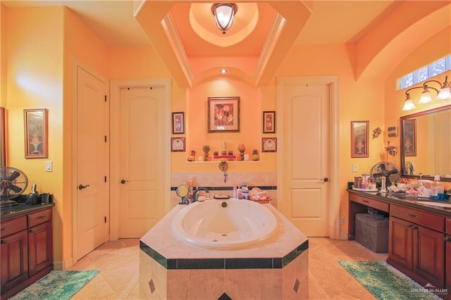 bathroom featuring a raised ceiling, tiled tub, and vanity