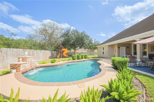 view of swimming pool with a playground, a patio area, and pool water feature