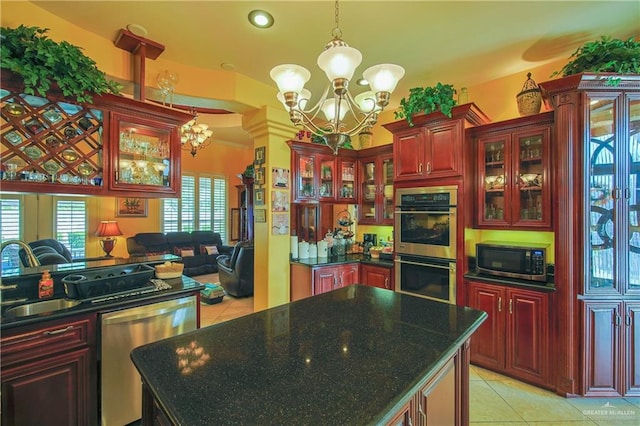 kitchen with sink, light tile patterned floors, appliances with stainless steel finishes, a notable chandelier, and a kitchen island