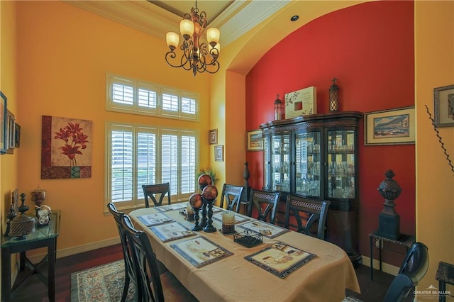 dining area featuring wood-type flooring, crown molding, a notable chandelier, and a high ceiling