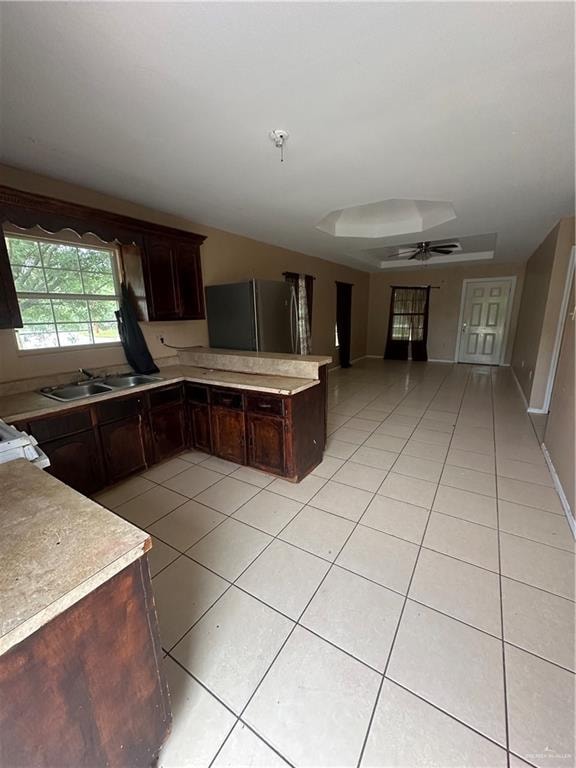 kitchen with dark brown cabinetry, sink, and refrigerator