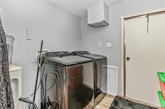 laundry room featuring a textured ceiling, washing machine and dryer, and light hardwood / wood-style flooring