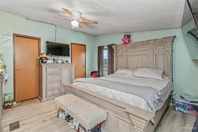 bedroom with a textured ceiling, ceiling fan, vaulted ceiling, and light wood-type flooring