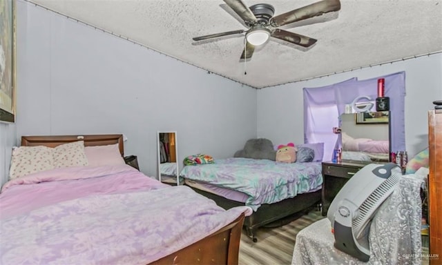 bedroom with ceiling fan, light hardwood / wood-style floors, and a textured ceiling