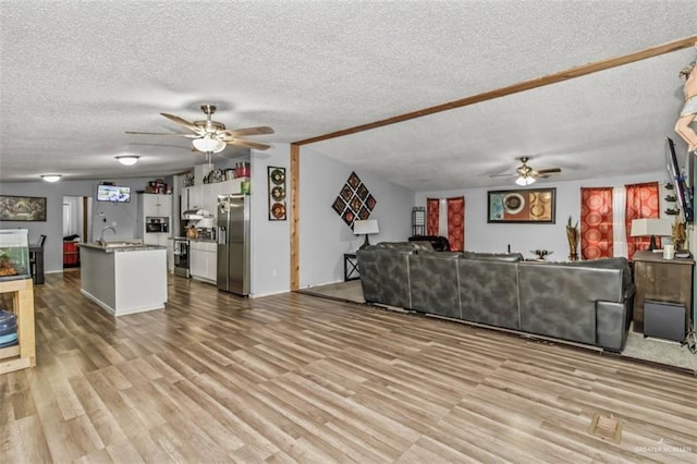 living room with ceiling fan, light hardwood / wood-style floors, and a textured ceiling