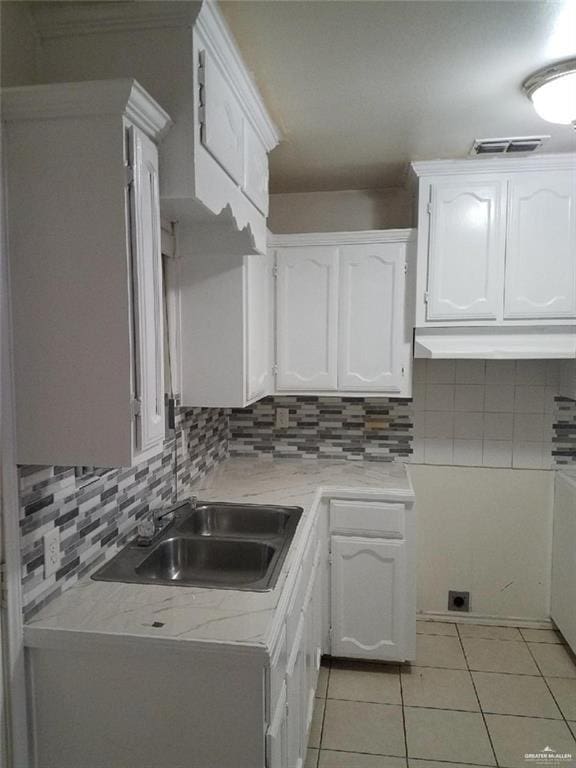 kitchen with decorative backsplash, sink, white cabinets, and light tile patterned floors