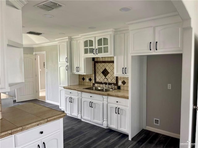 kitchen featuring visible vents, glass insert cabinets, a sink, and white cabinetry