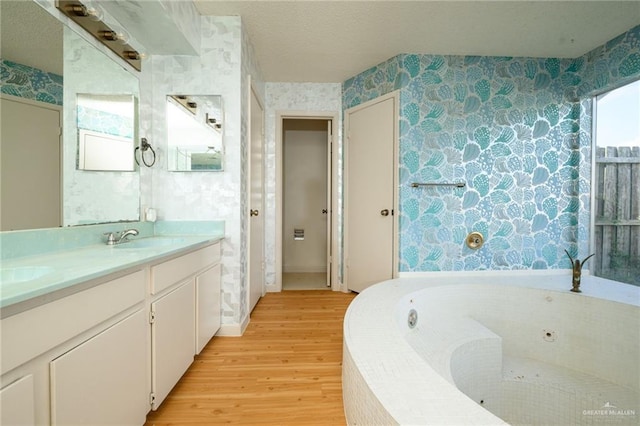 15220 Wilson Rd, Harlingen, TX 78552 - full bath featuring wallpapered walls, wood finished floors, double vanity, and a whirlpool tub
